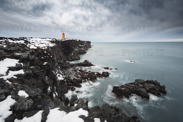 Orange lighthouse Ondverdarnes stands on a dark cliff