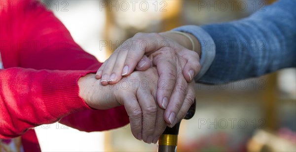 Girl puts her hand on the hands of an old woman with cane