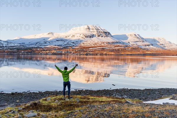 Man standing on the shore stretching his arms in the air