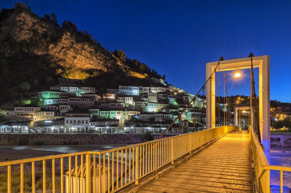 Illuminated Ottoman houses and modern bridge over Osum river at dusk