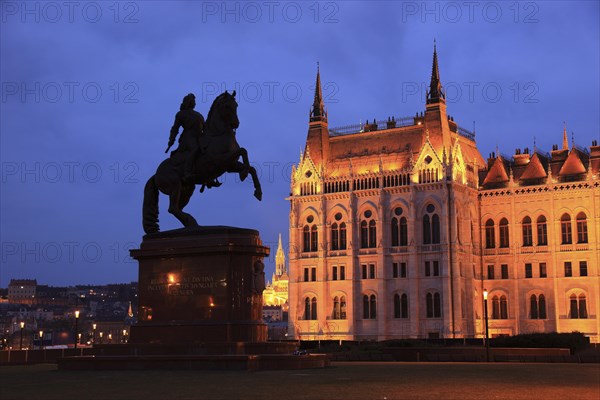 Illuminated parliament building with equestrian statue at dusk