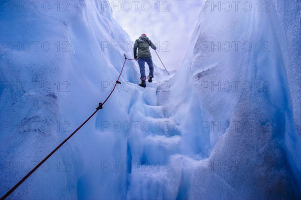 Woman walking steps out of a ice cave in Fox Glacier