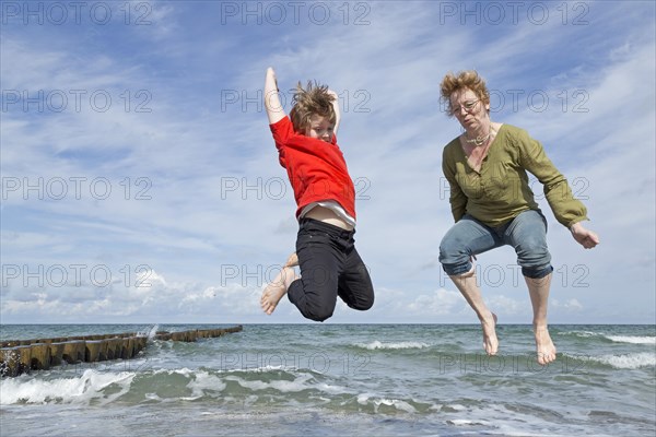 Mother and son jump on the beach