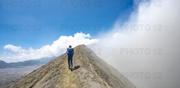 Young man on a narrow path at the crater rim