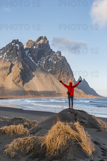 Man in red jacket stretches arms into the air