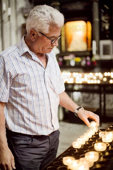 Grauhaariger Senior lights a sacrificial candle in the Koner Dom