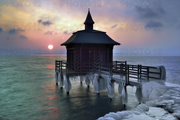 Bathhouse on pier with icicle in winter at sunrise