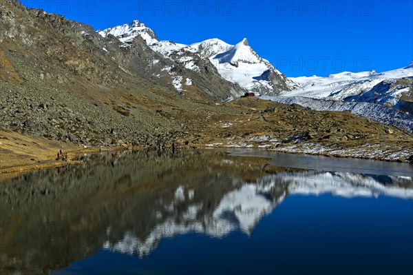 Lake Stellisee with view to the mountain restaurant Fluhalp and summits Adlerhorn and Zermatt