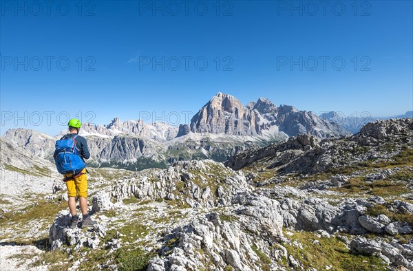 Hiker with climbing helmet on hiking trail to the Nuvolau