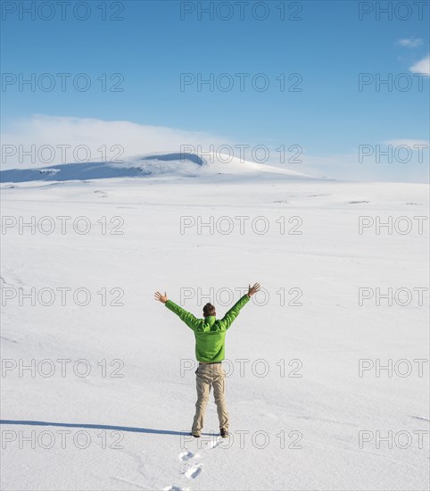 Young man stands alone in snowy landscape