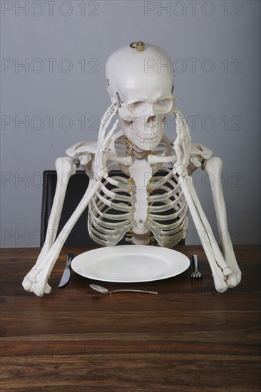 Skeleton with supported head sitting at table