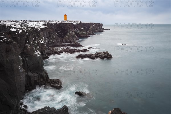 Orange lighthouse Ondverdarnes stands on a dark cliff
