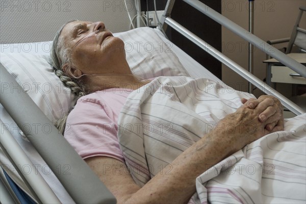 Sleeping senior citizen with respiratory tube in bed in hospital