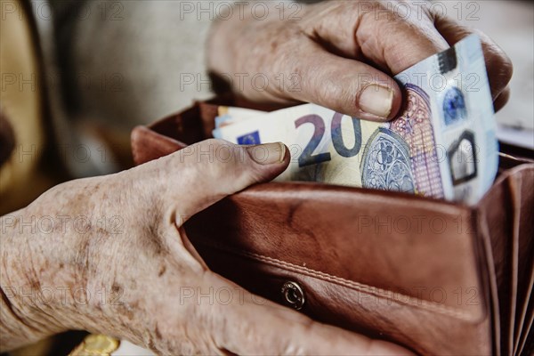 Senior citizen pulls a 20 euro note from her wallet