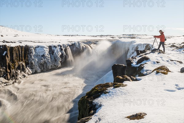 Photographing man at the edge of the Selfoss waterfall in winter