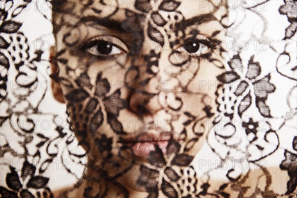 Face of a beautiful woman behind a transparent cloth with floral pattern