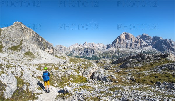 Hiker with climbing helmet on footpath to the Nuvolau