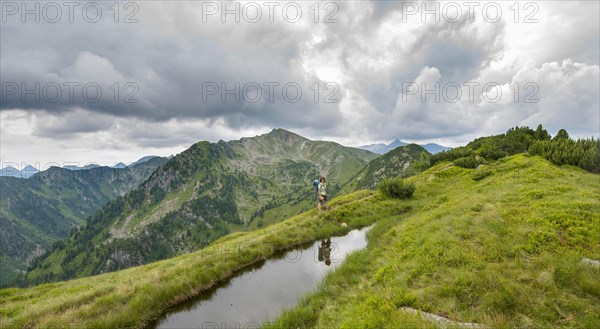 Hiker is reflected in a small lake