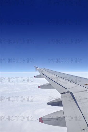Airplane wing above cloud cover wit blue sky
