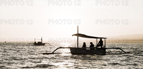 Silhouettes of outrigger boats in the ocean at sunrise