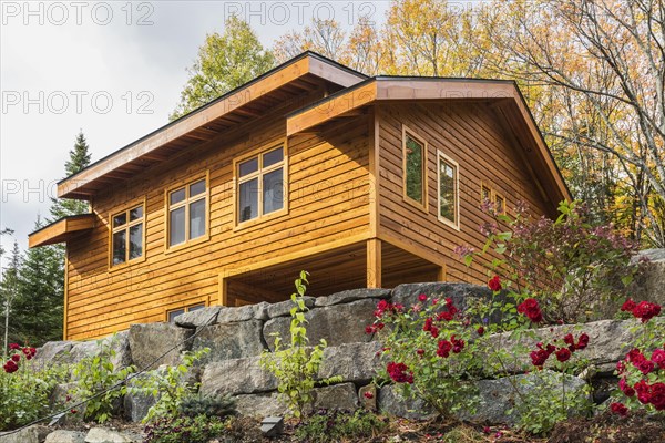 Luxurious stained cedar and timber wood 2-car garage with upstairs floor and landscaping in autumn