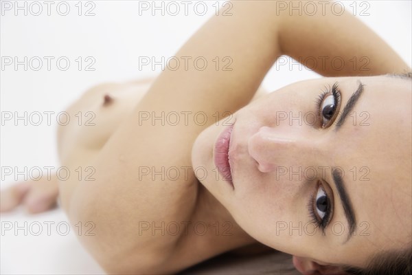 Young woman lying naked on a white background