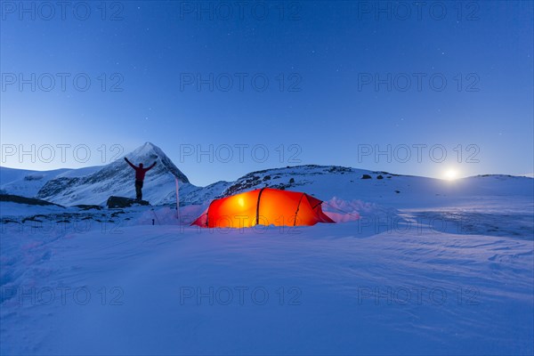 Tent with person at full moon in the snow