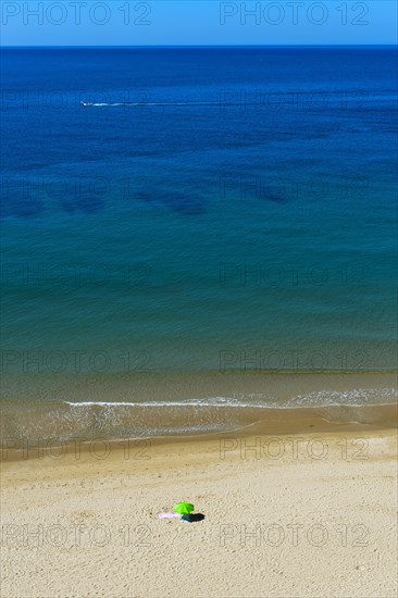 Solitary parasol on an empty sandy beach near Praia da Luz