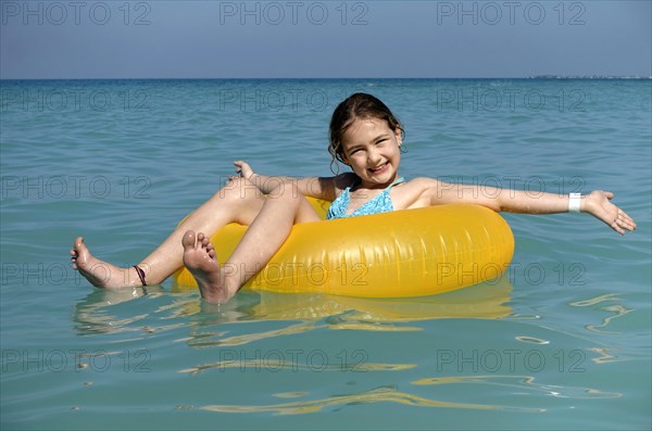 Child sitting happily in a floating tire in the sea