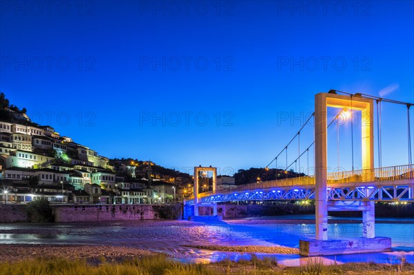 Illuminated Ottoman houses and modern bridge over Osum river at dusk