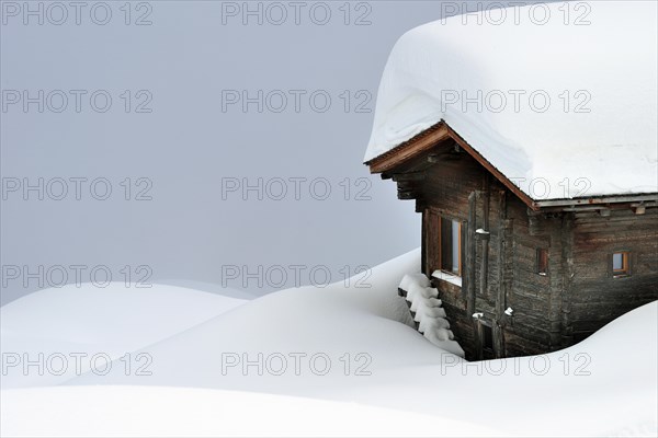 Snow-covered log cabin in the fog