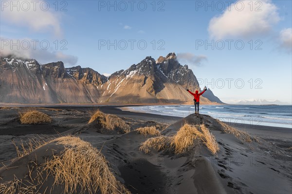 Man in red jacket stretches arms into the air