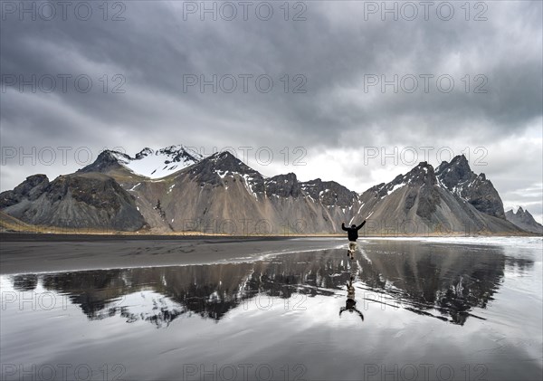 Hiker jumps at the black sandy beach