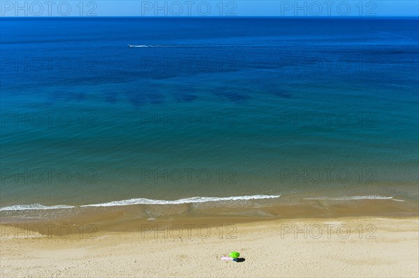 Solitary parasol on an empty sandy beach near Praia da Luz