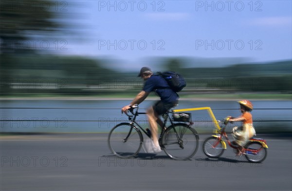 Cyclist and girl wearing bicycle helmet cycling