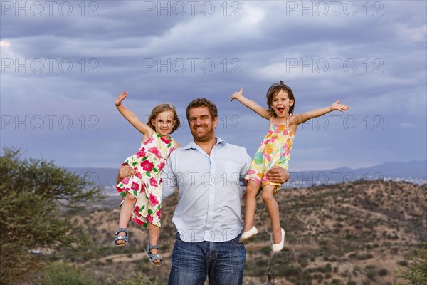 Father holding his two daughters in his arms