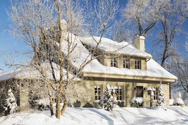 Old 1840s home facade with grey stone masonry and wood cladding plus Christmas decorations in winter