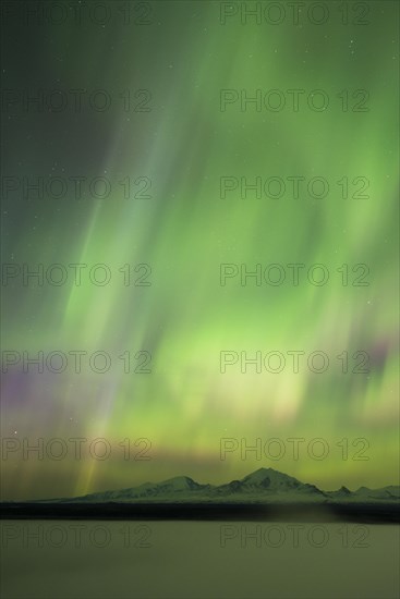 Aurora over the fog shrouded Copper River and mounts Sanford Drum and Wrangell