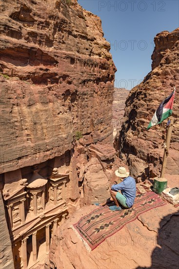 Tourist sits on a carpet and looks from above into the gorge Siq