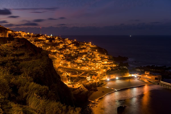 Blue hour with illuminated town by the sea