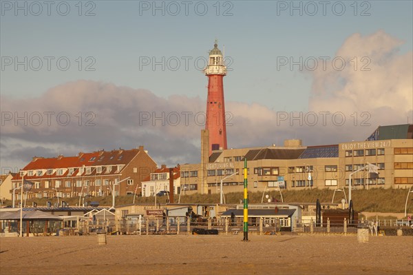 Lighthouse on beach behind buildings