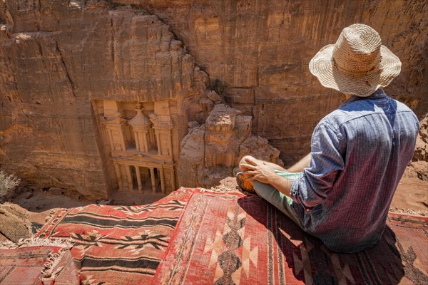 Tourist with sun hat sitting on carpet