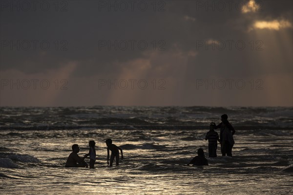 People in backlight in water