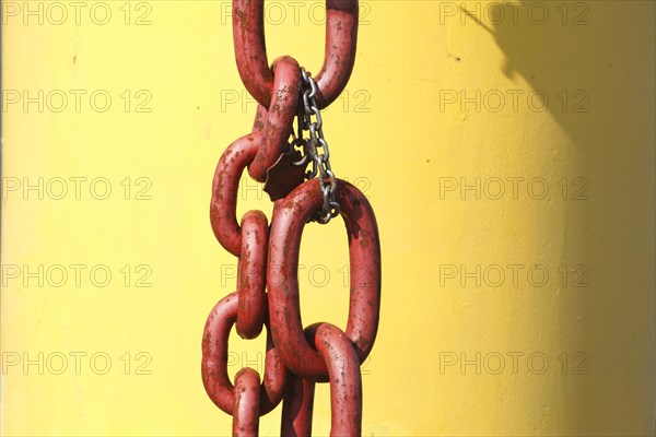 Red iron chain against yellow background