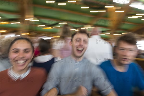 Three young people celebrate happily in a beer tent