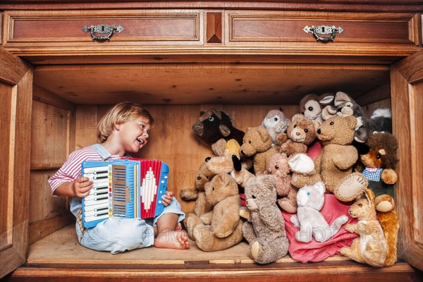 Five year old girl playing accordion for her stuffed animals