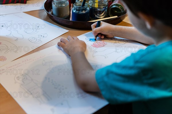 Child drawing with colored pencils in kindergarten