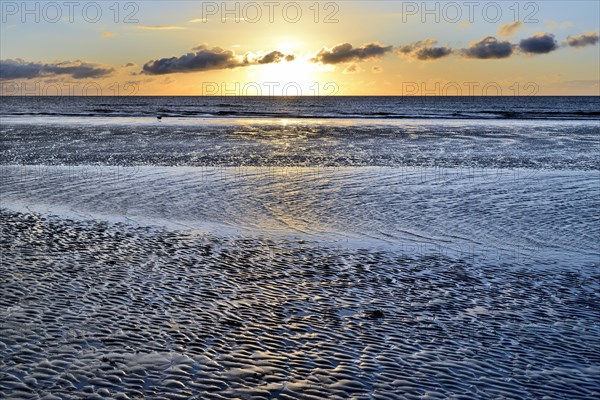 Sunset on sandy beach with wave-like structures