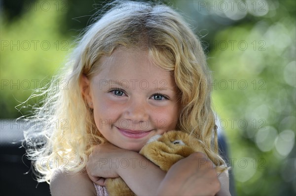 Little girl with blonde hair and cuddly toy