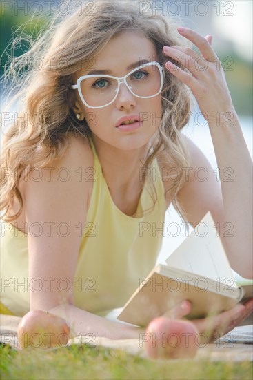 Young woman with book by river shore